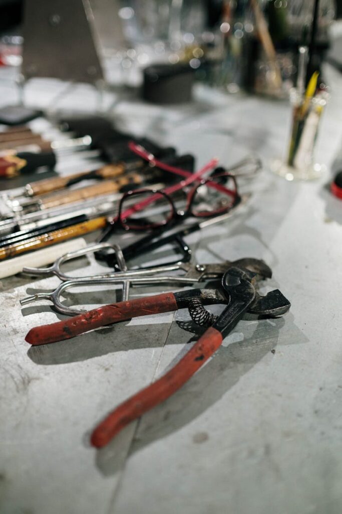 Close-up of assorted hand tools and eyeglasses on a workshop table. Ideal for craft and DIY inspiration.